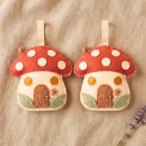 Two mushroom ornaments displayed side-by-side on a warm neutral linen fabric backdrop for a bundle listing view.