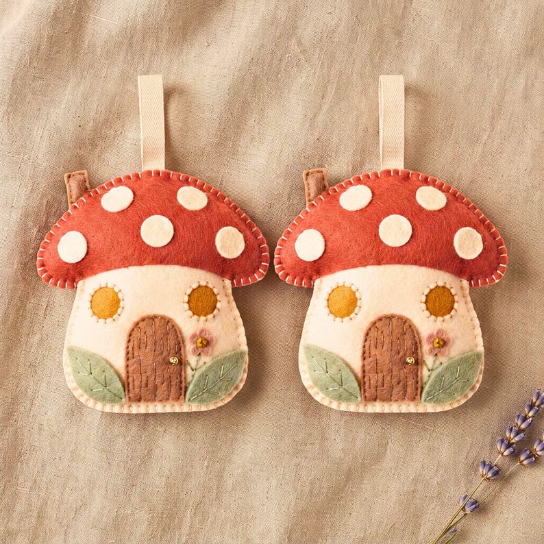 Two mushroom ornaments displayed side-by-side on a warm neutral linen fabric backdrop for a bundle listing view.