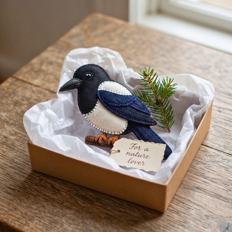 Felt magpie ornament hanging on a bookshelf with bird books and a fern