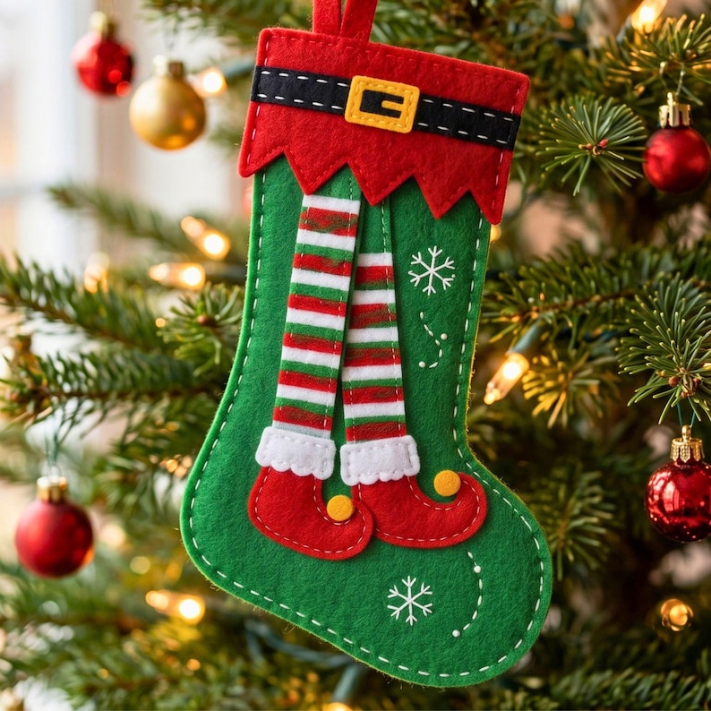 Finished green felt Christmas elf stocking ornament with red cuff, black belt, gold buckle, striped legs, curled red shoes and snowflake details.