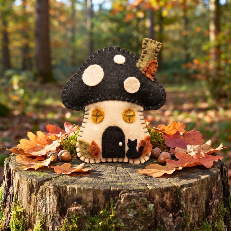 Felt mushroom house ornament in a fairy garden terrarium with moss and pebbles