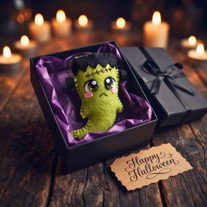 Green felt Frankenstein ghost ornament in a black Halloween gift box with purple tissue and ribbon.