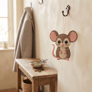 Finished Dumbo Rat felt sewing project featuring a rounded grey body, cream chest, pink hands and feet, large ears, and long curled tail.