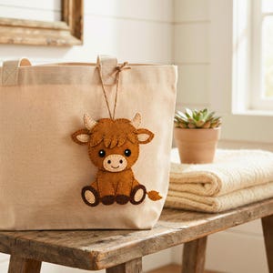 Cute brown Highland Cow felt ornament with cream snout and layered ears