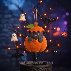 Felt cat in pumpkin ornament hanging on a black twig Halloween tree with orange fairy lights