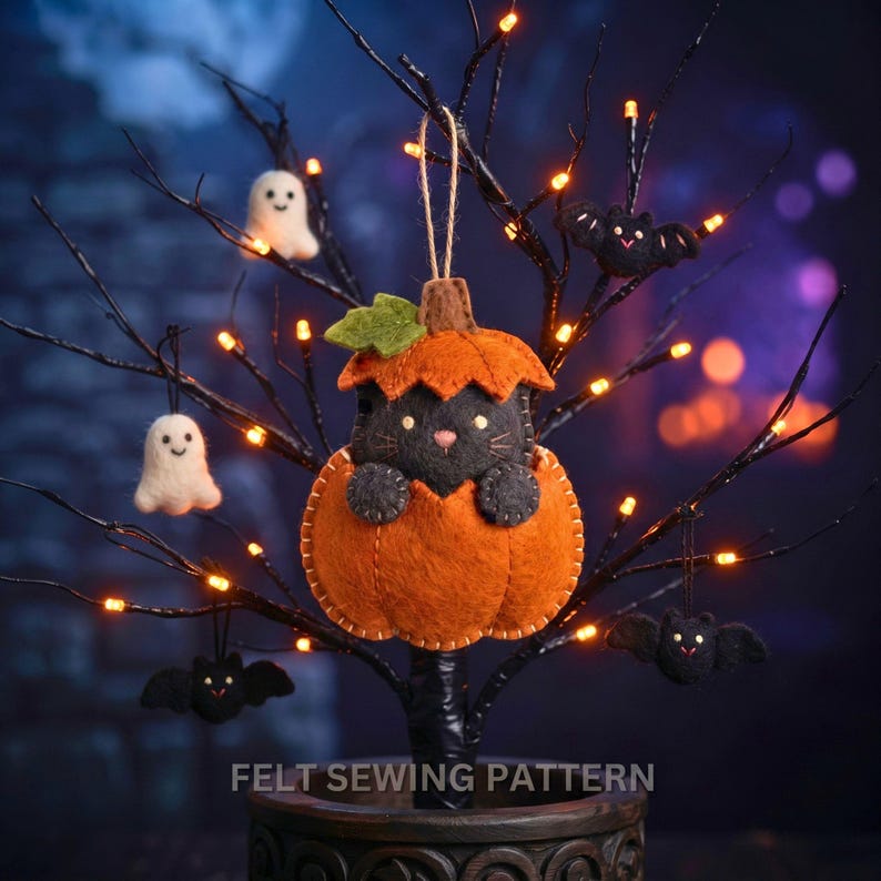 Felt cat in pumpkin ornament hanging on a black twig Halloween tree with orange fairy lights