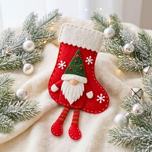 Handmade felt Christmas gnome stocking showing the red stocking body, white cuff, green hat, beard, legs, shoes and decorative details.