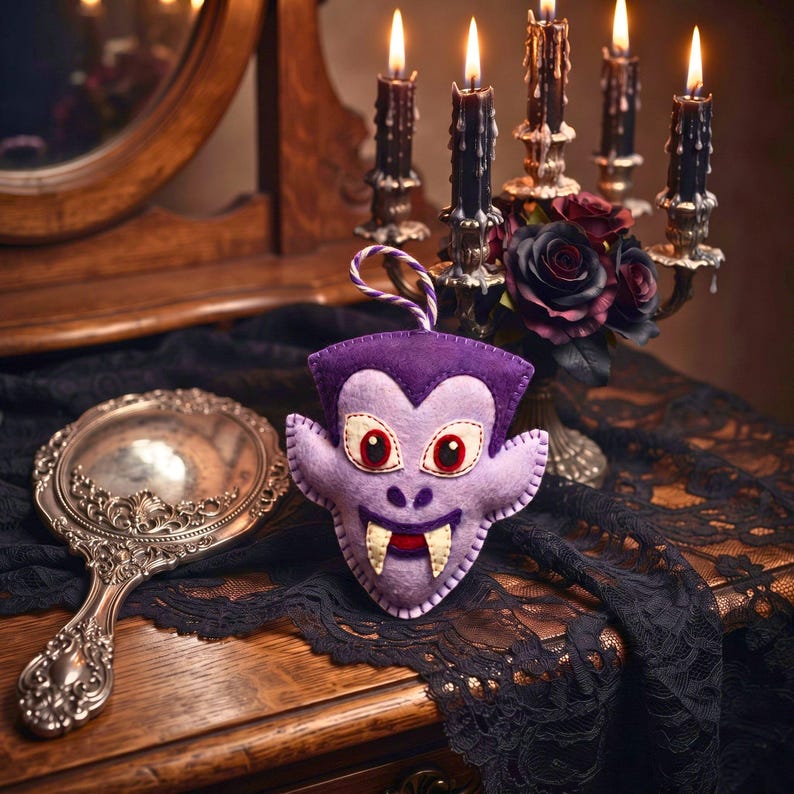Felt vampire Halloween ornament on a vintage vanity with a mirror, black lace, candles and dark roses.