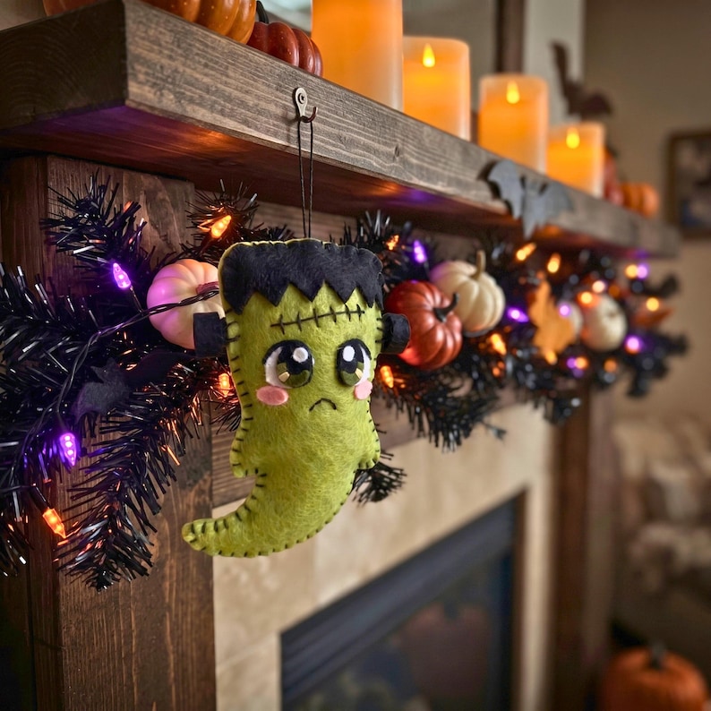 Green felt Frankenstein ghost ornament hanging on a black Halloween tree with purple fairy lights.