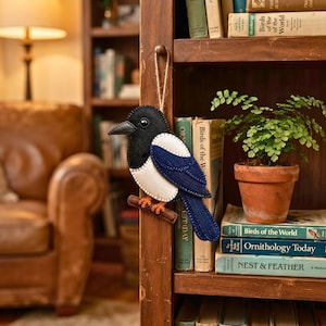 Felt magpie ornament in a gift box with tissue paper and a pine sprig