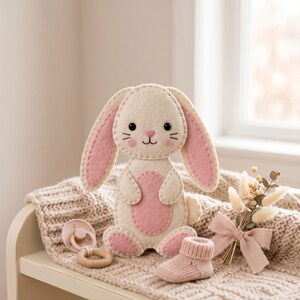 Handmade felt bunny ornament shown from another view, featuring white and cream felt, soft pink inner ears and chest, pink feet details, and a hanging loop.