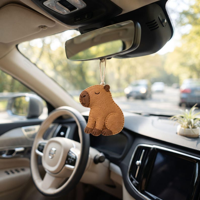 Handmade capybara felt ornament in warm tan and dark brown felt with a rounded body, sleepy embroidered eyes, snout, paws and hanging loop.