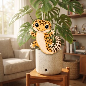 Hand-sewn leopard gecko felt ornament showing the long curled tail, spotted body, small arms and legs, cream feet, and detailed felt construction.