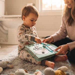 Mother and toddler playing together with an interactive felt quiet book page about dental hygiene.
