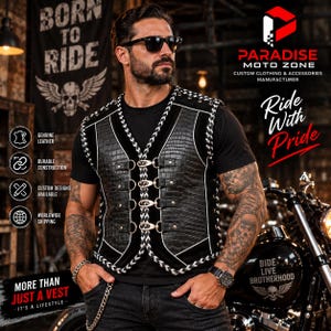 Op de afbeelding: Een zwart vest met een textuur van krokodillenleer, witte gevlochten randen en vier zilverkleurige metalen gespen aan de voorzijde. Het vest wordt gedragen over een effen zwart T-shirt in combinatie met een donkere spijkerbroek en ketting.