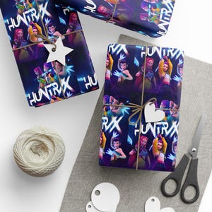 Puede incluir: Papel de regalo con un patrón repetitivo de personajes animados con cabello y atuendos coloridos, junto con el texto "HUNTRAX" en una fuente blanca en negrita. El papel está atado con cordel marrón e incluye etiquetas blancas en forma de estrella y corazón.