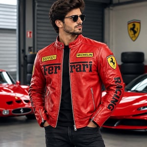 Puede incluir: Una chaqueta de cuero rojo brillante con parches negros de las marcas Ferrari y Michelin en el pecho, un logotipo grande de Ferrari en la manga y la palabra RACING impresa en negro a lo largo del brazo. Tiene cuello alzado y cremalleras plateadas.