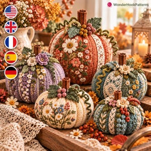 May include: A collection of five crocheted pumpkins in orange, lavender, cream, and blue, each featuring intricate floral embroidery, lace trim, green crocheted leaves, berries, and brown stems, arranged together on a wooden surface.