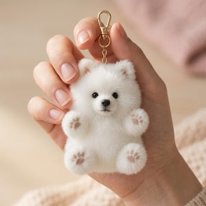 May include: A white, fluffy, plush dog keychain featuring a small, round bear-like body, black eyes, a black nose, and light pink paw pads on its feet. The keychain is attached to a gold-toned metal lobster clasp and a short chain link.