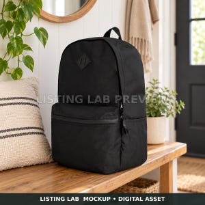 May include: A solid black backpack featuring a main compartment, a front zippered pocket, and a small diamond-shaped patch on the upper front panel. The bag has a top handle and side pockets, with a clean, structured design for daily utility.