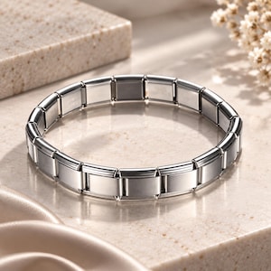 Peut inclure: Un bracelet à maillons modulaires argenté composé de multiples segments métalliques rectangulaires reliés par des ressorts internes. Le bracelet présente une surface polie et réfléchissante sur chaque maillon, formant un anneau continu.