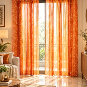 Peut inclure: Une paire de rideaux orange transparents ornés d'un motif répétitif blanc composé de cercles et de formes géométriques. Les rideaux sont suspendus à une tringle dorée par des pattes en tissu et descendent du plafond au sol, filtrant la lumière.