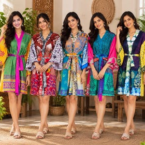 May include: Five short robes featuring vibrant, multi-coloured patterns and prints. Each robe has wide sleeves, a V-neckline, and a matching fabric tie belt at the waist. The designs include floral, geometric, and abstract motifs in various colours.