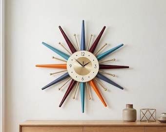 May include: A starburst wall clock featuring a central circular face with a gold-toned center and white border, displaying black numerals at 3, 6, 9, and 12. The clock has radiating spikes in alternating colors of blue, orange, and deep red.