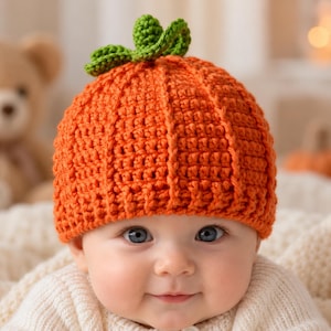Può includere: Un berretto all'uncinetto color arancione brillante progettato per assomigliare a una zucca, caratterizzato da una trama a coste verticali e un piccolo stelo verde lavorato all'uncinetto con foglie attaccate sulla parte superiore centrale.