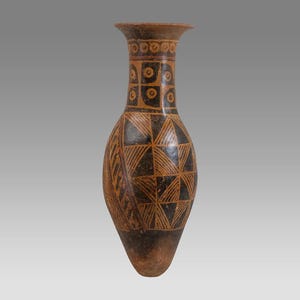 May include: A tall, slender ceramic vase with a flared rim, featuring a dark brown and tan color palette. The surface is decorated with geometric patterns, including repeating circles in the neck and a grid of triangles on the body.