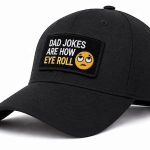 May include: A black baseball cap featuring a rectangular patch on the front. The patch is black with white text that reads DAD JOKES ARE HOW, followed by the word EYE ROLL in yellow text next to an emoji of a yellow face with eyes rolled upward.