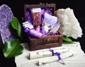May include: A wooden treasure chest filled with purple and white items, including dried herbs, a small bottle of glitter, and a small bottle of liquid. The chest is open and sitting on a white surface with a scroll that says "How to Make Your Own Invisible Ink!"