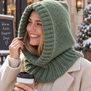 May include: A sage green knitted hood with a wide ribbed trim that extends into a cowl neck. The knit texture is consistent throughout the piece, featuring a thick, soft yarn construction that frames the face and covers the neck area completely.