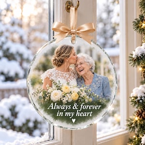 May include: A circular glass ornament featuring a photograph of a person in a white lace dress kissing an older person in a blue jacket. A bouquet of yellow and white flowers is at the bottom with the text Always & forever in my heart.