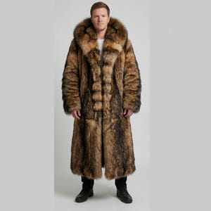 May include: A long, full-length coat made of thick, textured faux fur in shades of brown, tan, and black. The garment features a large, voluminous hood, long sleeves, and a straight-cut silhouette that extends down to the lower calf area.