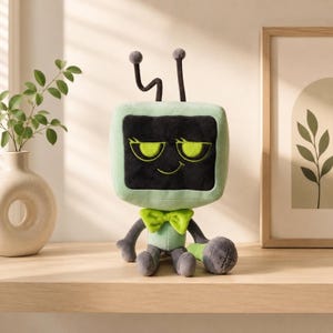 May include: A plush toy shaped like a television set with a light green body and a black screen featuring embroidered lime green eyes and a smirk. It has two dark gray antennae on top, a lime green bow tie, and a small gray microphone accessory.