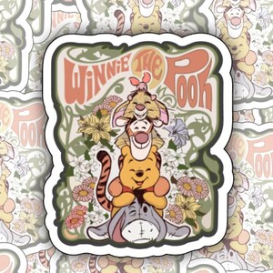 May include: A set of 16 Winnie the Pooh stickers featuring a vintage-style illustration of Winnie the Pooh, Piglet, and Tigger with a floral background. The stickers are white with a black outline and have a glossy finish.