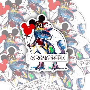 May include: A set of colorful stickers featuring a cartoon dinosaur wearing sunglasses and a Mickey Mouse hat, holding a red balloon. The dinosaur is surrounded by colorful paint splatters and the text "WRONG PARK" is written on the sticker.