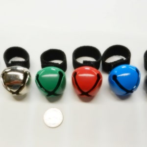 May include: Six jingle bells with black elastic bands. The bells are gold, silver, green, red, blue, and black.