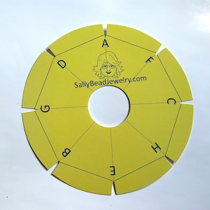 May include: A yellow, circular bead weaving tool with a central hole and segmented sections labeled A through H. The tool features a logo and website address: SallyBeadJewelry.com.