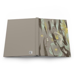 May include: An open hardcover book with a solid light gray back cover featuring a small square QR code in the bottom corner. The front cover displays an abstract illustration with dark brown, light blue, and yellow brushstroke patterns.