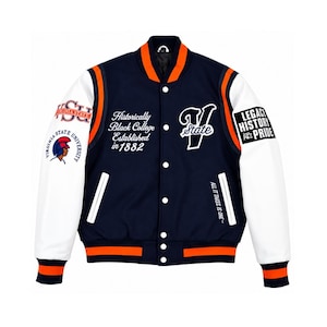 Op de afbeelding: Een marineblauw en wit varsity jack met oranje gestreepte geribbelde boorden. De voorzijde bevat de tekst "Historically Black College Established in 1882" en "V State". De mouwen tonen "Virginia State University" en "LEGACY HISTORY PRIDE".