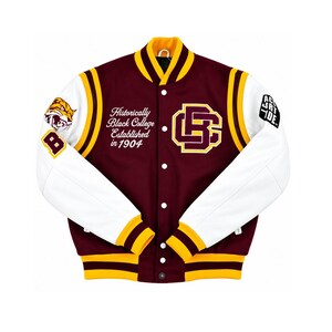 May include: A maroon and white varsity jacket featuring yellow striped ribbed trim on the collar, cuffs, and hem. The front displays the text "Historically Black College Established in 1904" and a large "BC" logo. A tiger graphic and "B" are on the right sleeve.