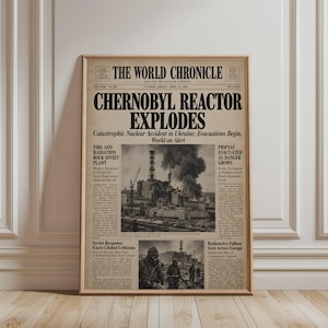 Könnte beinhalten: Ein gerahmter Zeitungsdruck mit dem Titel The World Chronicle vom Freitag, den 25. April 1986. Die Schlagzeile lautet Chernobyl Reactor Explodes und zeigt ein Schwarz-Weiß-Foto des beschädigten Kraftwerks mit Rauch und Personen in Schutzkleidung.