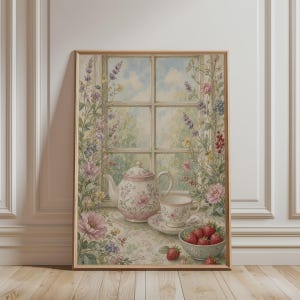Op de afbeelding: Een ingelijste muurkunstprint met een witte theepot en bijpassend theekopje met roze bloemmotieven, geplaatst op een tafel bij een raam. De scène bevat een kom met verse rode aardbeien en omringende wilde bloemen in tinten roze, paars en groen.