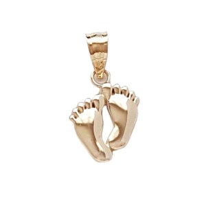 May include: A polished gold pendant shaped like a pair of small baby feet. The charm features a smooth, reflective surface and includes a tapered, textured bail at the top for attachment to a necklace chain or bracelet.