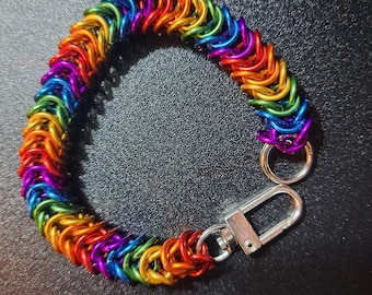 May include: A rainbow-colored chainmail bracelet with a silver clasp and jump rings. The bracelet is made of small, interlocking metal rings in a spectrum of colors, including red, orange, yellow, green, blue, and purple.