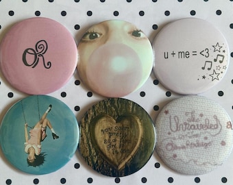May include: A set of six circular pin-back badges featuring various designs: a pink badge with black 'OR' text, a face blowing a bubble, a white badge with 'u + me = <3' and stars, a person on a swing, a heart in a tree, and 'The Unraveled' text.