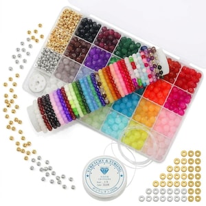 May include: A clear plastic storage container filled with assorted colourful round beads in various shades including red, blue, green, yellow, and purple, alongside metallic gold and silver beads, a spool of clear elastic cord, and loose beads.