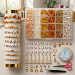 Op de afbeelding: Een sieradenmaakset met een doorzichtige plastic opbergdoos gevuld met diverse kralen in oranje, goud en witte tinten, een cilindrische standaard met tien armbanden, losse letterkralen, kwastjes, gouden sluitingen, 0,8 mm elastisch koord en een schaar.